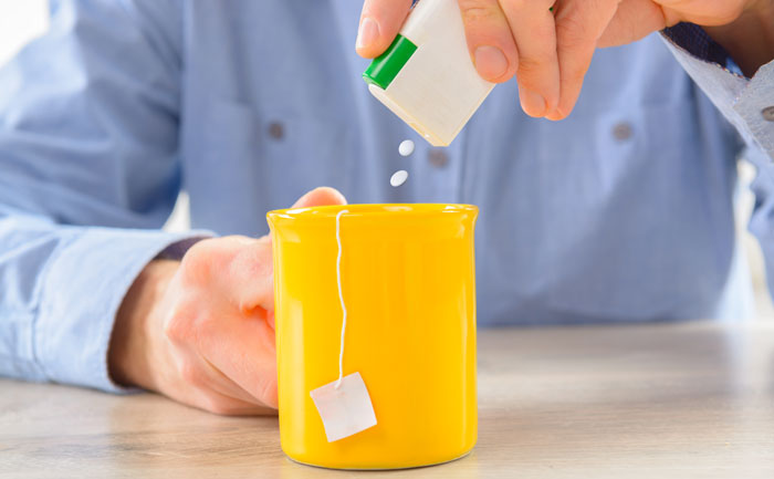 Homme qui ajoute de l'aspartame à son thé